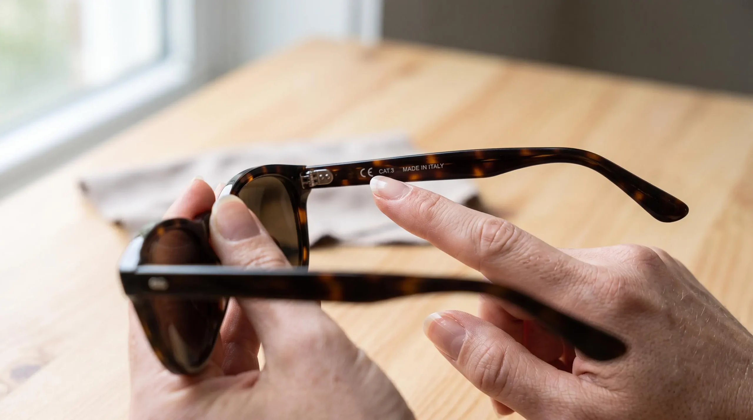 Des mains examinent le marquage de catégorie sur la branche d'une paire de solaires.